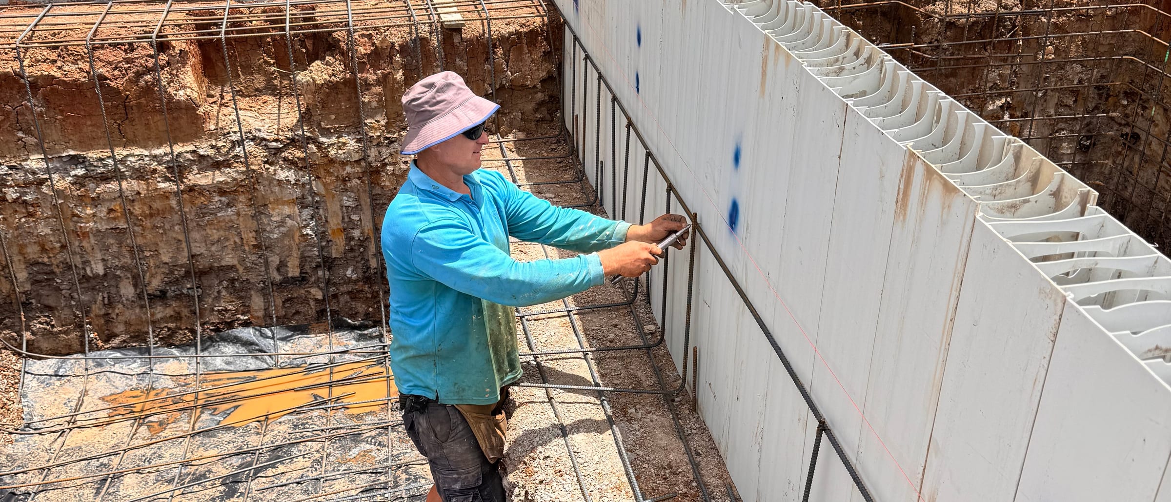 Zac fixing steel reinforcement inside a pool excavation, on a Tectonic Pools site